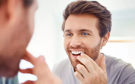 Man looking at his smile in the mirror